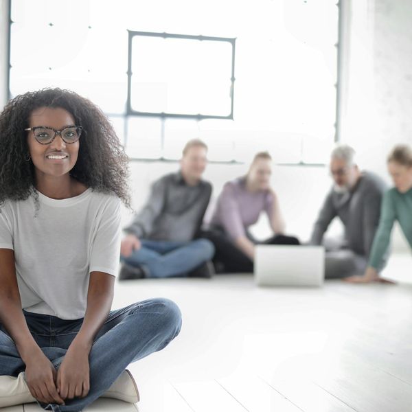 A diverse group of smiling office workers in a modern, bright workspace.