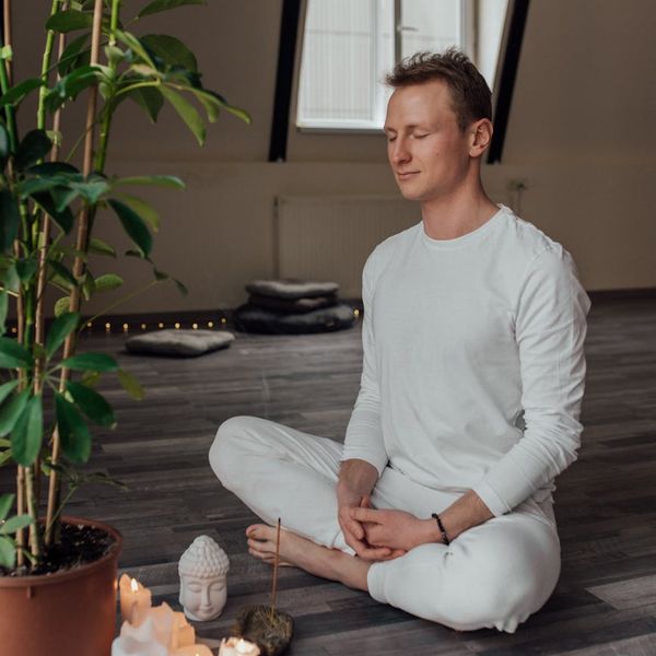 Person sitting cross-legged with eyes closed in a moment of calm meditation.